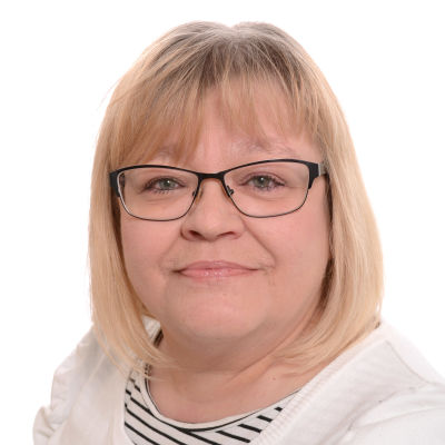 Kvinna med glasögon och blont hår som tittar rakt in i kameran.