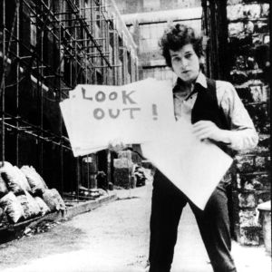 Bob Dylan esittelee sanakylttejä "musiikkivideossa" Subterranean Homesick Blues, taustalla Allen Ginsberg. Kuva D.A. Pennebakerin ohjaamasta dokumenttielokuvasta Don't Look Back (1967).