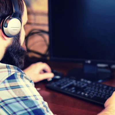 En person med hörlurar på jobbar framför en dator. 