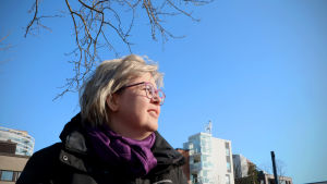 Maria Myllynen njuter av andningsluften, som är renare i år. Gatudammet gör ändå att luften har skadliga partiklar. Maria Myllynen tittar upp på en blå himmel