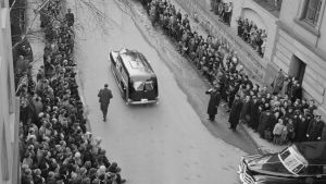 Begravningen av kronprinsessan Märtha, bilden tagen 5.4.1954. Begravningen av kronprinsessan Märtha. Svart bild med kistan medan folk flockas kring gatan.
