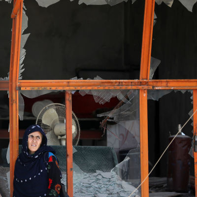 En afghansk kvinna står framför en söndrigt fönster efter en bombattack i västra Kabul.