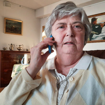 Äldre kvinna som håller en mobiltelefon mot öra.