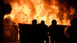 Kvällarna präglas av mer oroligheter. Brand under protester i Barcelona. Mot lågorna ser man siluetten av tre huvuden.