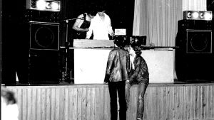 Unge dj Måsse till vänster i Kyrkslätt cirka 1978. Vad önskade tjejerna för låtar månntro? En mycket ung Måns Strömberg med kompis som dj på svartvitt foto. Två tjejer står framför scenen.