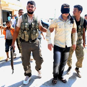 Alla inblandade har gjort sig skyldiga till människorättsbrott vad beträffar personer som fängslats, enligt FN. Bild på två män i militär utrustning som gripit en man i vit skjorta och ögonbindel.