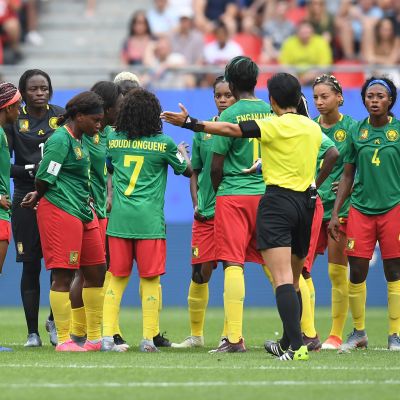 En domare försöker få Kameruns damlandslag att fortsätta matchen.