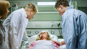 Lääkäri ja potilas katselevat sairaalasängyssä makaavaa potilasta.