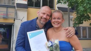 Matias Jungar och Malin Valtonen står tillsammans med Sam Stäuber för produktionen Närmat i Västnyland. Bild av leende Matias Jungar och Malin Valtonen med diplom och blombukett i handen.