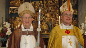 Biskop Gustav Björkstrand och ärkebiskop Jukka Paarma vid Björkstrands vigning. Biskop Gustav Björkstrand och ärkebiskop Jukka Paarma klädda i biskopsskrudar och med mitra och stav sida vid sida framför altaret i Pernå kyrka.