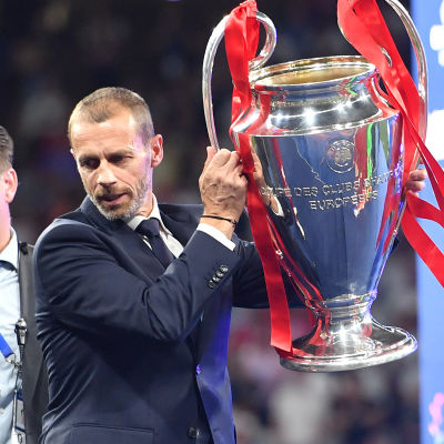 Aleksander Ceferin lyfter upp Champions League-bucklan från ett bord.