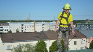 Antti Tervo uppe på taket. Antti Tervo står vid takkanten av ett sjuvåningshus i Vasa.