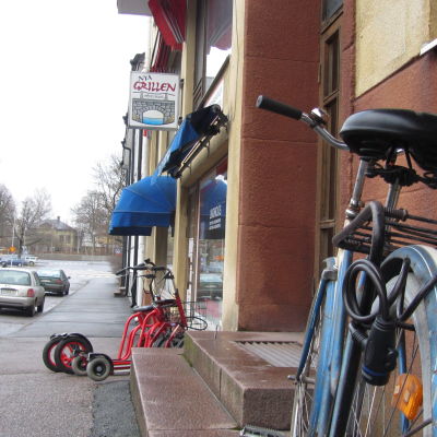 En gata med några parkerade rollatorer och en cykel utanför en dagcentral.