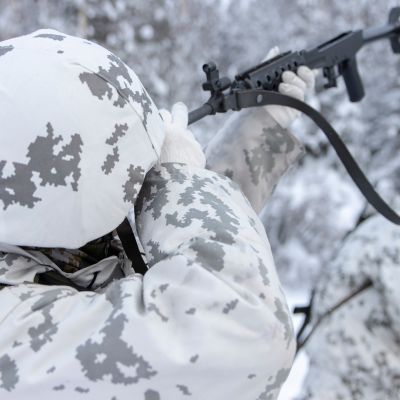 Varusmies huoltaa rynnäkkökivääriä talvisessa metsässä