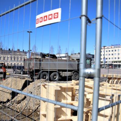 Kuva Mikkelin torilta, jonne rakennetaan torilavaa. Kuvassa rakennustyömaa-aita, jonka takana tehdään perustustöitä.