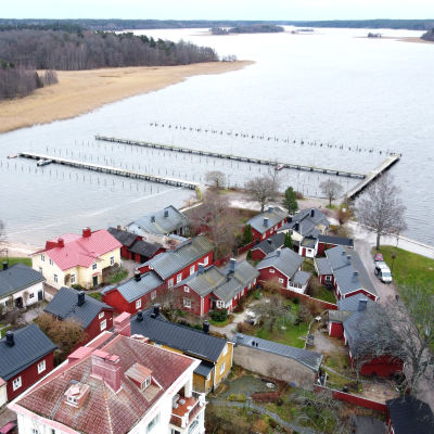 Flygbild över Barckens udde i Ekenäs. Man kan se en del av Gamla stans hus och bryggorna och pålar vid vattnet.