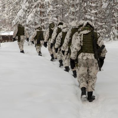 Alokkaat kulkevat jonossa lumisessa metsässä polkua pitkin aseet olalla