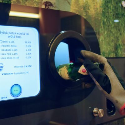 David Stephensin käsi laittamassa pulloa palautusautomaattiin. Automaatin näyttö kertoo, että hän on palauttanut pulloja yli kaksi sataa ja rajaa on melkein 40 euroa.