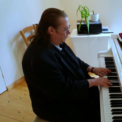 Kassu Halonen soittaa valkoista flyygeliä.