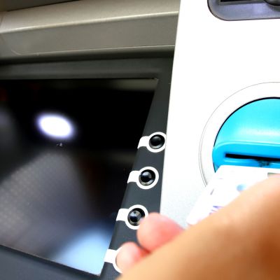 Käsi työntää pankkikorttia automaattiin