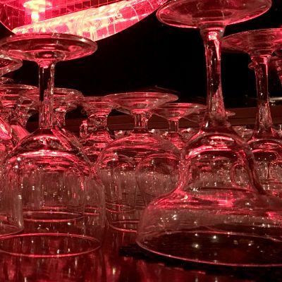 Erilaisia lasisia juomalaseja, kuten konjakki- ja viinilaseja, punaisessa valossa.