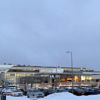 Päijät-Hämeen keskussairaala talvisena päivänä. Lunta, parkkipaikka täynnä autoja, sairaalarakennusten ikkunoissa valot.