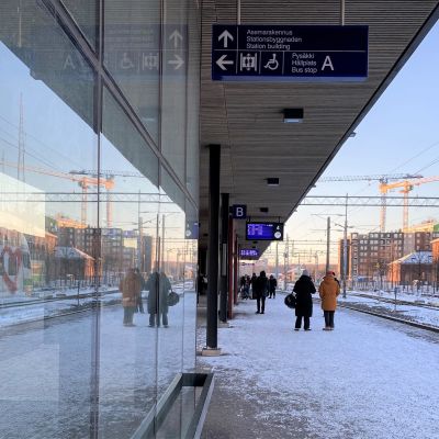 Lahden rautatieasema, tyhjät raiteet, raiteiden vieressä ihmisiä odottamassa junaa raiteille. Talvi, lunta. 
