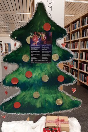 Julgubbens hjälpredas träd i Pargas bibliotek är redan en tradition. En grönmålad julgran i papp med presenter under står i ett bibliotek.