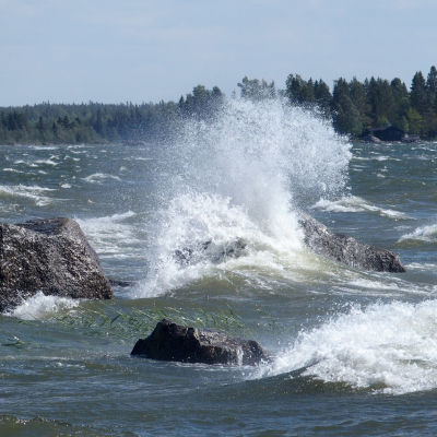 Vågor slår mot strandstenar i hård vind. 