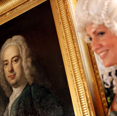 Dam i peruk visar upp en tavla som föreställer Georg Friedrich Händel