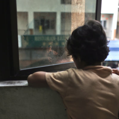 Ett barn tittar ut genom ett fönster.