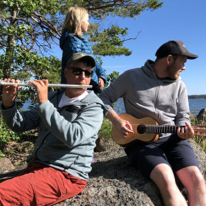 Pasi Hiihtola, dottern Liv och skivans producent Mikael Grönroos Pasi Hiihtola, Mikael Grönroos och Livs sitter på en strandsten