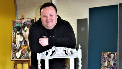 medelålserman lutar mot en stol och ler mot kameran