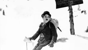 Charles Chaplin hätääntyneen näköisenä lumihangessa elokuvassa Kultakuume.