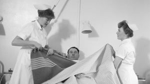 Ett utbyggt sjukvårdssystem förlängde finländarnas livslängd med ett decennium. Två sjuksköterskor vårdar en manlig patient.