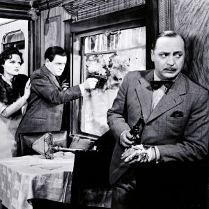 Kaksi miestä ja nainen ovat linnoittautuneina junan ravintolavaunuun: toinen miehistä nojailee seinään ase kädessä, toinen tähtää pistoolilla rikkinäisestä ikkunasta ulos, nainen seisoo hänen takanaan.
