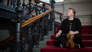 viulisti Pekka Kuusisto istuu viulu kädessä portaikossa