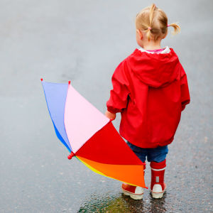 Barn i regnkläder håller i ett paraply