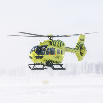 En räddningshelikopter i färd att landa på en snöig landningsplats.