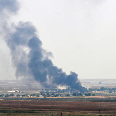 Den syriska gränsstaden Rads al-Ain brinner. På bilden syns staden på långt avstånd och svart rök som stiger upp från den. 