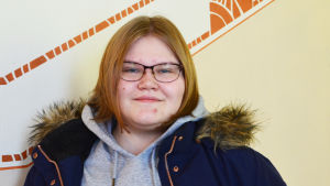 Christel Still går första året i gymnasiet. En ung kvinna står i en trappa. Hon tittar in i kameran och ler.