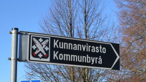 En skylt där det står kommunbyrå. Det finns också en bild av Pyttis vapen på skylten, det är två korsade fiskar mot svart botten.