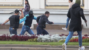 Civilklädda män gick till attack mot demonstranter under söndagen. Två batongbeväpnade män jagar en en tredje man.