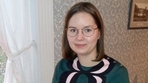 Ella Airola skrev sin pro gradu om unga och Youtube. Ella Airola sitter vid ett caféfönster.