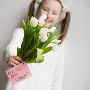 Tyttö ojentaa äitienpäiväkukkia