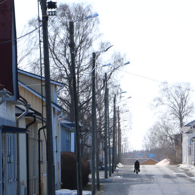 En gata i Kaskö med trähus på båda sidorna. En ensam cyklist skymtar fram på vägen.