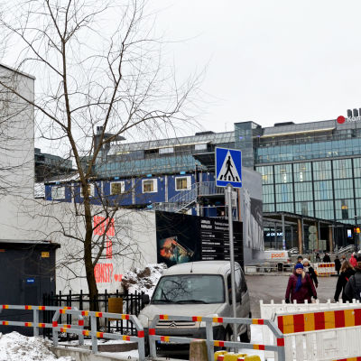 Glaspalatsets pilträd omgett med byggställningar, med Narinken och Kampens köpcentrum i bakgrunden.