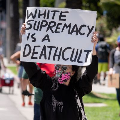 En kvinna håller upp en skylt där det står "vit makt är en dödskult".