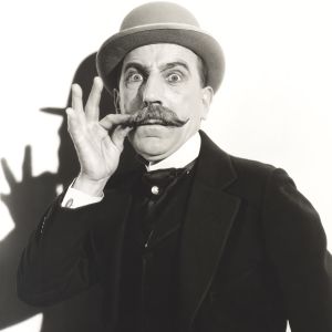 En man med en stor mustasch och en fin hatt.