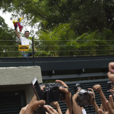 Oppositionsledaren Leopoldo López håller i Venezuelas flagga och hälsar på sina anhängare från en bro i Caracas, Venezuela den 8 juli 2017.
